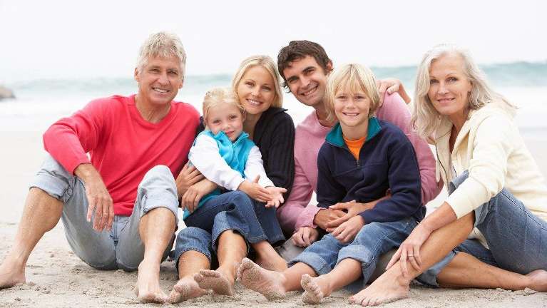 large family on beach smiling | dentist near me